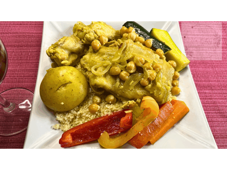A plate of Tunisian couscous with chicken and colorful vegetables.