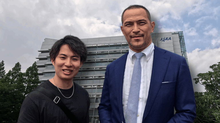 A photo of Koji Murofushi and the author with the JAXA building in the background, capturing a powerful moment of strength and space exploration