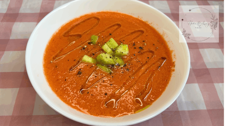 A bowl of Spanish gazpacho topped with cucumber, olive oil, and black pepper