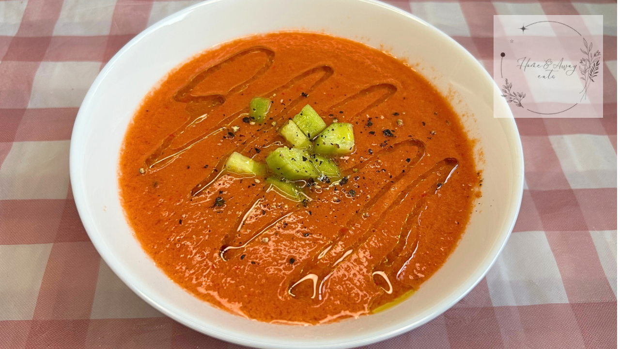 A bowl of Spanish gazpacho topped with cucumber, olive oil, and black pepper