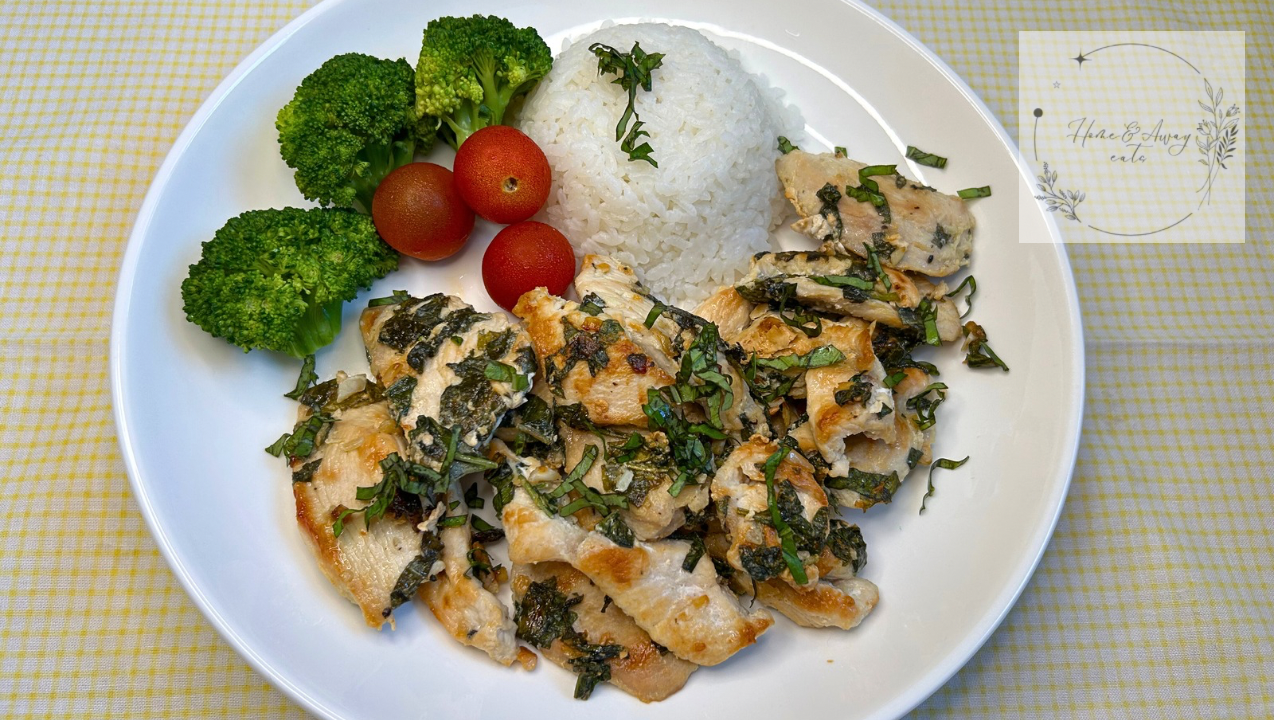 Sliced basil chicken breast served with rice and vegetables on a clean white plate.