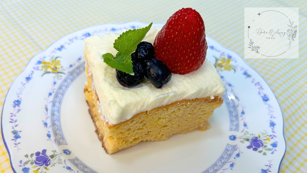 A slice of authentic Tres Leches Cake topped with whipped cream, fresh fruit, and mint