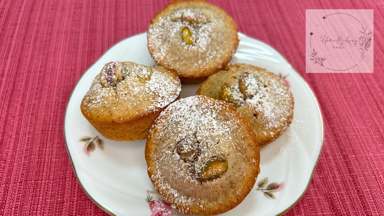 A batch of golden brown French financiers with pistachio toppings.