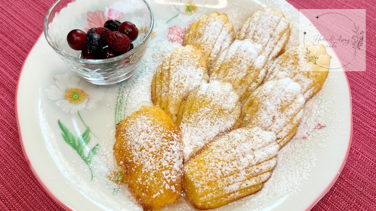 A plate of golden French madeleines dusted with powdered sugar