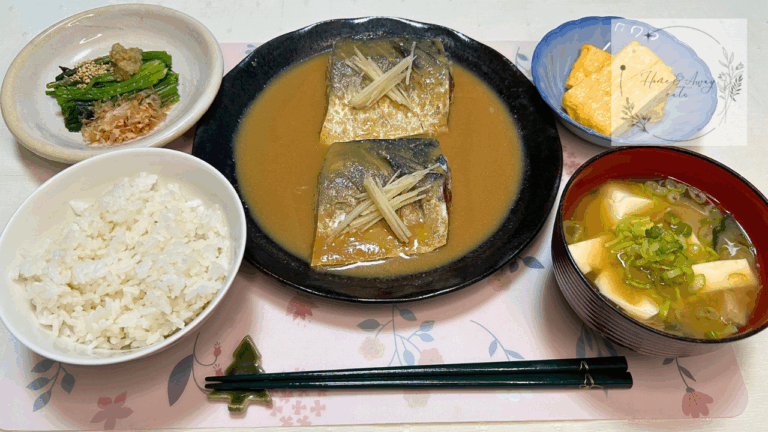 A Japanese set meal with miso-simmered mackerel, rice, miso soup, and traditional side dishes.