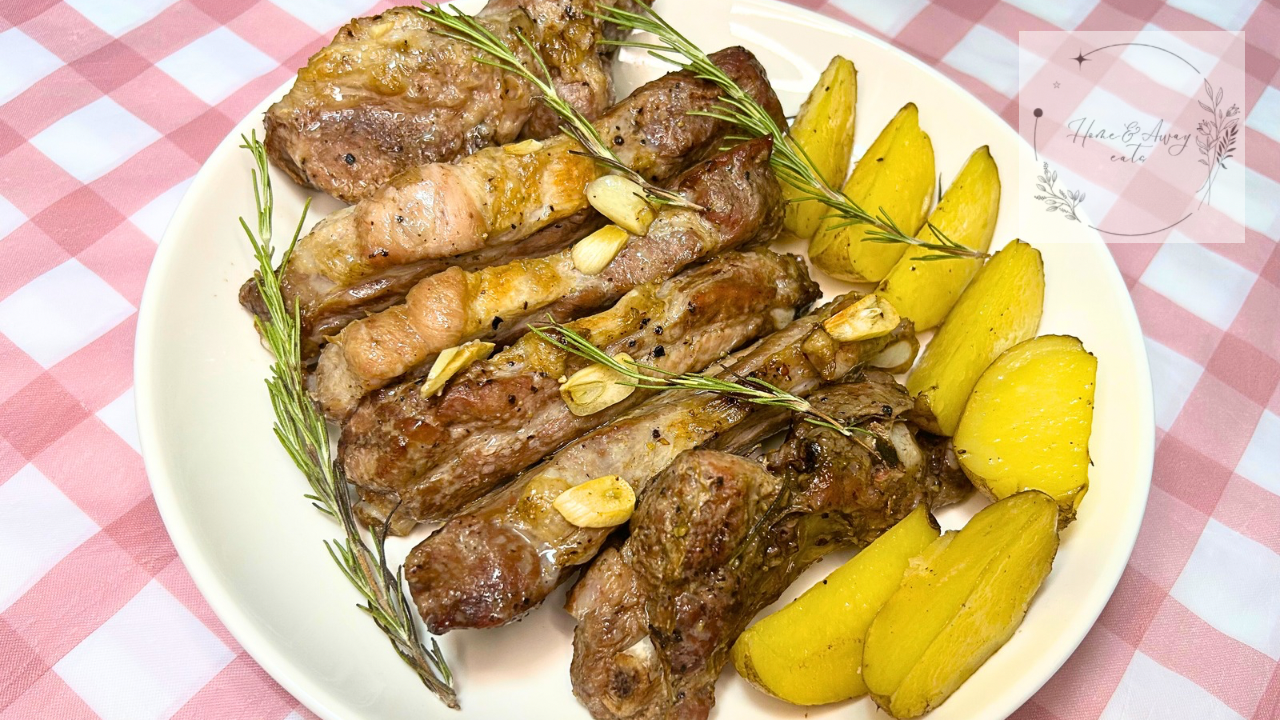 Italian oven ribs and potatoes served hot on a plate with roasted garlic and fresh rosemary