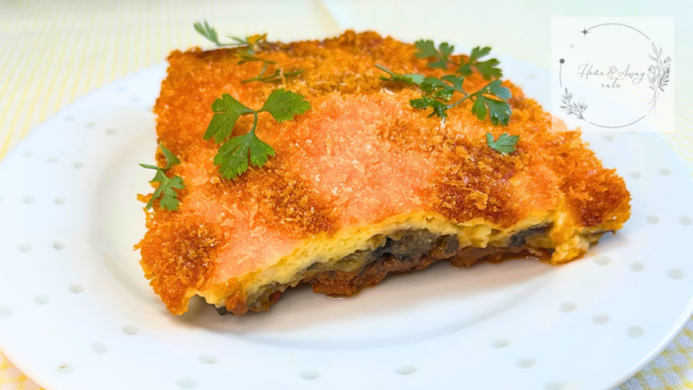 A sliced piece of Greek moussaka showing layers of eggplant, meat sauce, and béchamel on a plate.