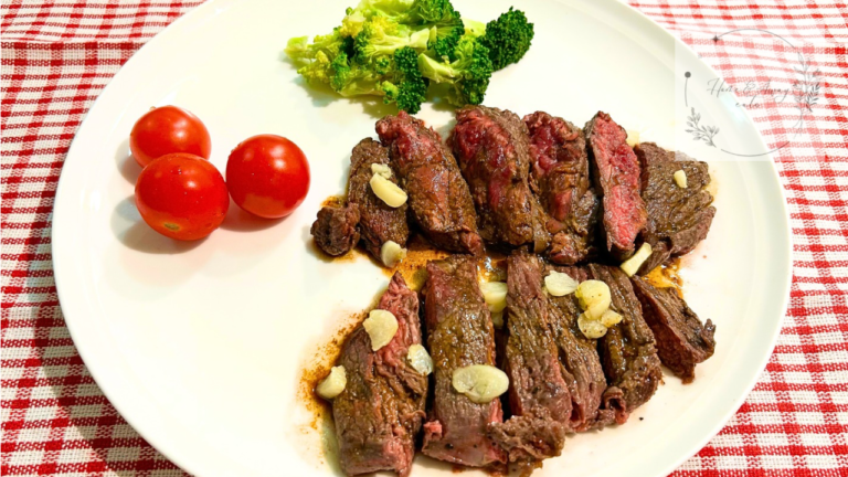 Sliced kangaroo steak served with garlic and vegetables on a plate